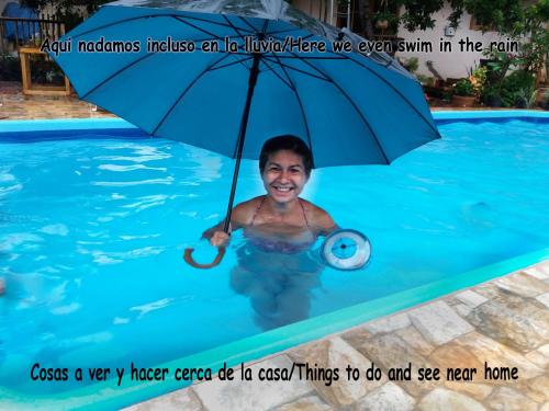 a woman in a swimming pool with an umbrella at Vacaciones Aregua CASA VANESSA in Areguá