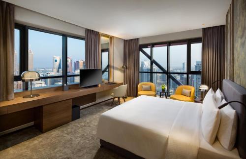 Millennium Place Barsha Heights Hotel في دبي: غرفة فندقية بسرير ومكتب مع تلفزيون