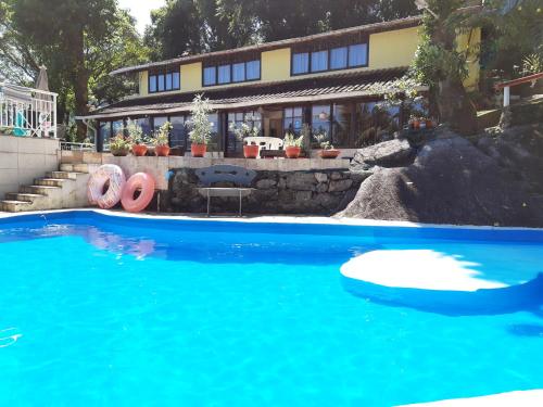 a large blue swimming pool in front of a house at Pousada Chale da Montanha in Petrópolis