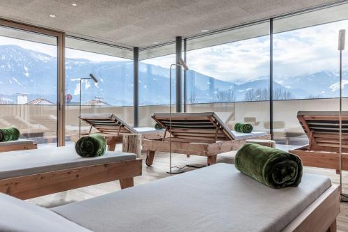 a room with benches and windows with mountains in the background at Hotel Restaurant Langgenhof in Brunico