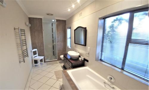 a bathroom with a tub and a sink and a window at Besigheim in Stellenbosch