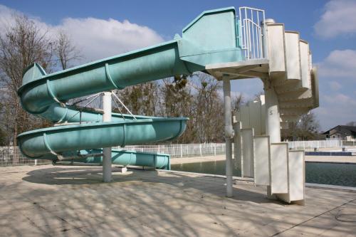 a green water slide in a park with a slide at The Petite Chalet Chambre d'hôtes in LʼIsle-Jourdain