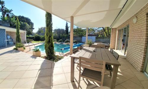 un patio con mesa, sillas y piscina en Besigheim, en Stellenbosch