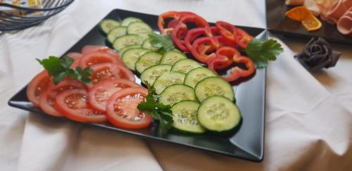 a black plate with cucumbers and tomatoes on a table at Hotel Altberesinchen in Frankfurt/Oder