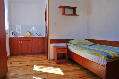 a bedroom with a bed and a wooden floor at Baltic Resort Darłówko - Domek nr 2 in Darlowko