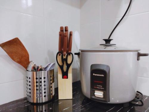 a counter top with a pot and a pair of scissors at Sea Lion Kuala Selangor Semi-Detached Homestay in Kuala Selangor