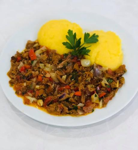 a plate of food with meat and a mashed potato at Pensiunea Valurile Bistritei in Vatra Dornei