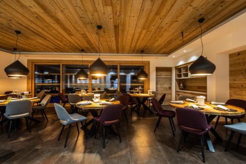 a restaurant with wooden ceilings and tables and chairs at Monaco Sport Hotel in Santo Stefano di Cadore