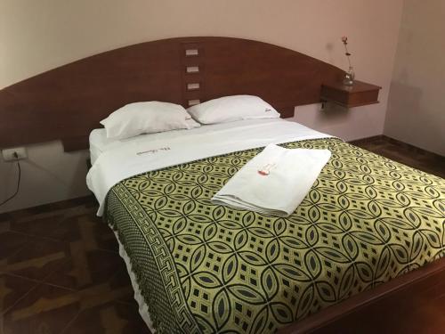 a bedroom with a large bed with a wooden headboard at Tamaris Hotel in Chiclayo