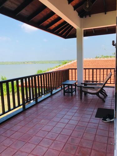 a porch with a bench and a view of the water at Ashansa Lagoon Resort in Tangalle