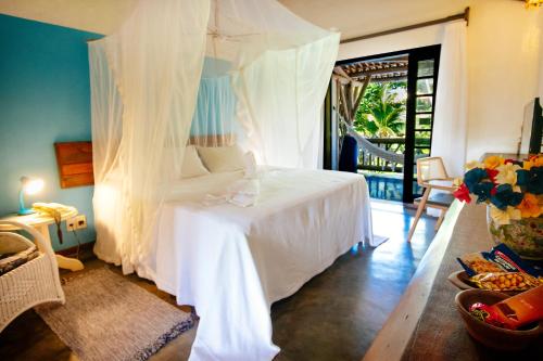 a bedroom with a bed with a canopy at Pousada Farol das Tartarugas in Praia do Forte