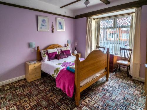a bedroom with a bed with purple walls and a window at The Tudor Lodge in Skegness