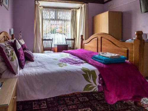 a bedroom with a large bed with purple walls at The Tudor Lodge in Skegness