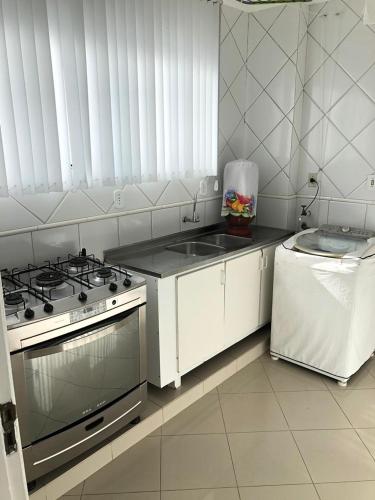 a kitchen with a stove and a refrigerator at Apartamento amplo, arejado e confortável - Mínimo 3 noites in Ilhéus