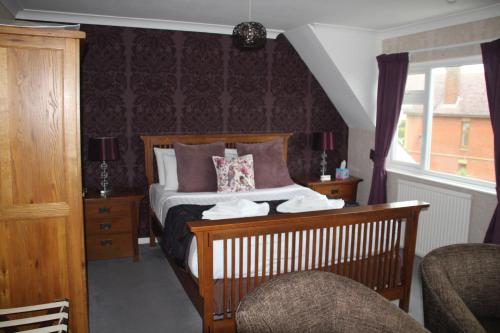 a bedroom with a bed and a chair and a window at The Kenbury B&B in Shanklin