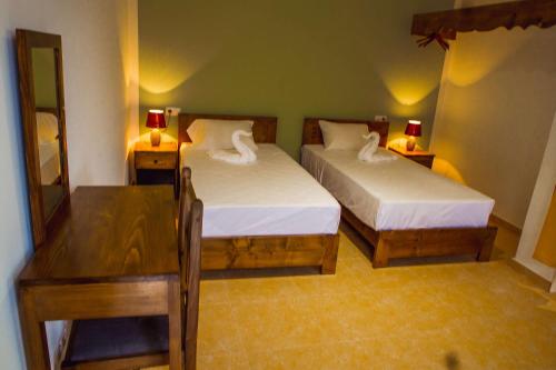 a bedroom with two beds and a table and a desk at Pousada Green Place in Ribeira Grande