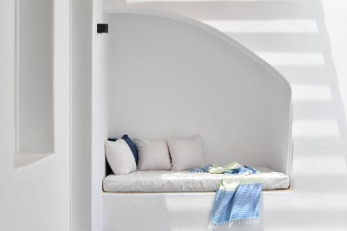 a white couch sitting under an archway in a room at Thiro Santorini in Fira