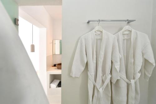 a white robe hanging on a rack in a bathroom at Thiro Santorini in Fira