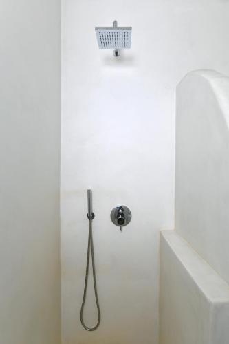 a shower in a white bathroom with a shower head at Thiro Santorini in Fira