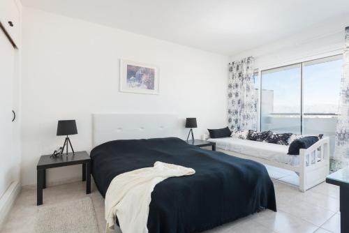 a white bedroom with a bed and a window at Apartamento Carole in Port d'Alcudia