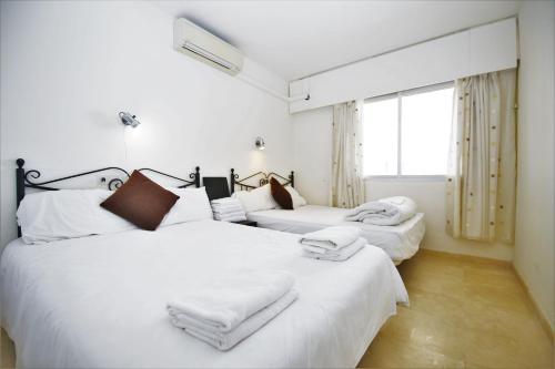 2 bedden in een kamer met witte lakens en handdoeken bij Apartment PP33 in Estepona