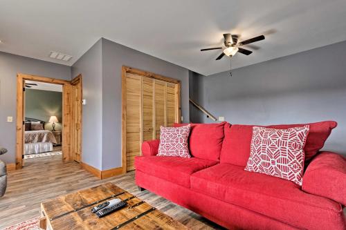 a red couch in a living room with a ceiling fan at Elevated Cabin Bordering Smoky Mountain Natl Park in Bryson City