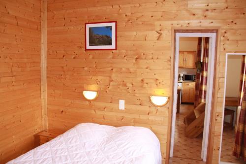 a bedroom with a wooden wall with a bed in it at Residence des Domes in Murol