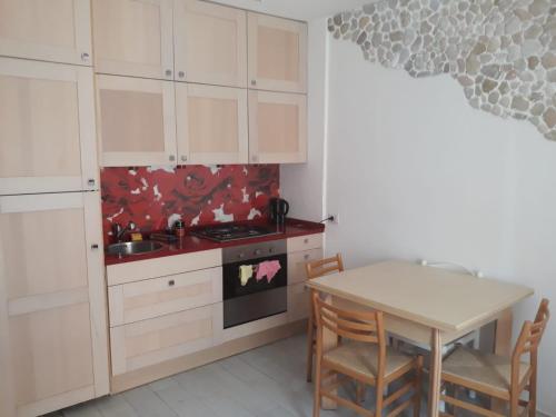 uma cozinha com armários brancos e uma mesa com cadeiras em Casa al mare em Lido di Fermo