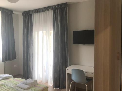 a bedroom with a bed and a desk and a window at Oázis Panzió in Gyenesdiás