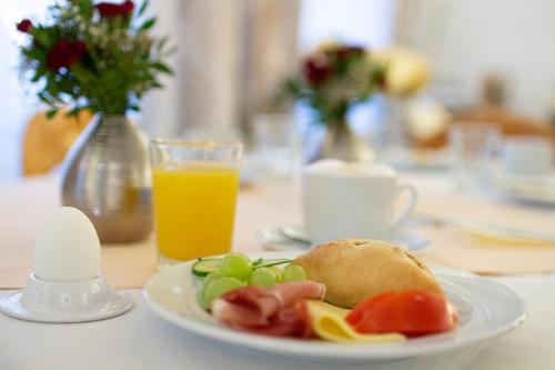 a plate of food on a table with a glass of orange juice at Hotel am Malerwinkel in Wertheim
