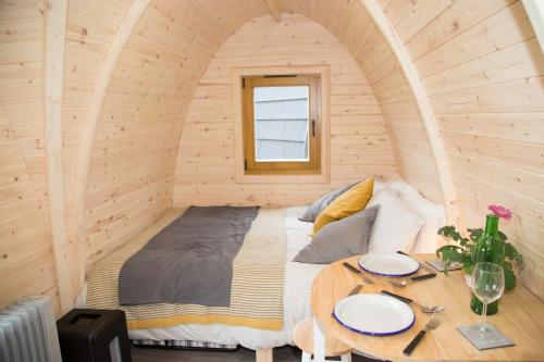 a bed in a wooden room with a table at Clova pod, Kilry eco pods in Blairgowrie