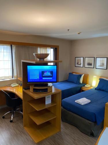 a hotel room with two beds and a television at Charmoso Flat na Faria Lima in Sao Paulo