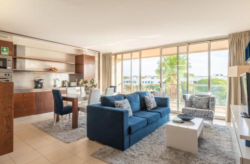 a living room with a blue couch and a kitchen at Herdade dos Salgados Vila das Lagoas in Albufeira