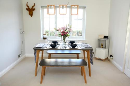 a dining room table with a vase of flowers on it at Modern Stylish Cambridge Pad (Free Parking) in Histon