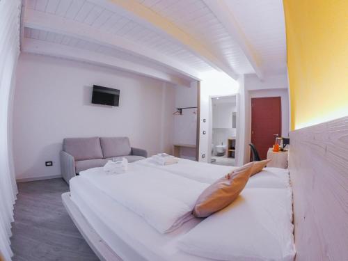 a large white bed in a room with a couch at Agritur Verderame in Trento