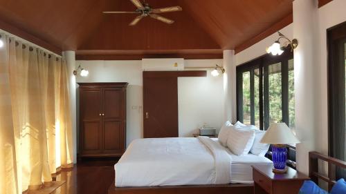 a bedroom with a white bed with a ceiling fan at Casa Khaoyai Bed&Breakfast in Mu Si
