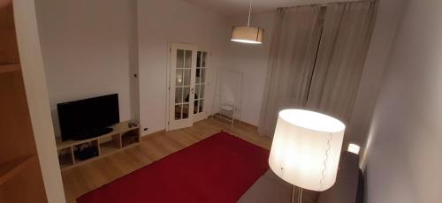 uma sala de estar com uma televisão e um tapete vermelho em Genio em Bolonha