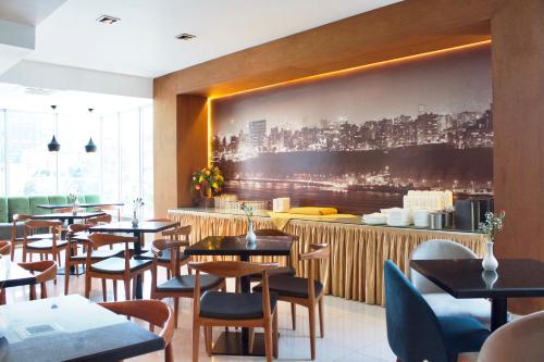 a restaurant with tables and chairs and a large painting on the wall at Habitat Hotel in Lima