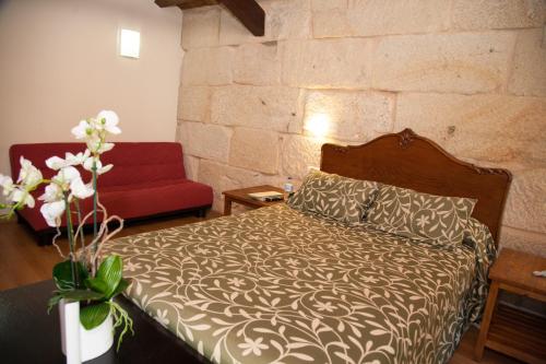 a bedroom with a bed and a red couch at Hotel Boa Vila in Pontevedra