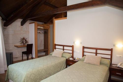 Un dormitorio con dos camas y un escritorio y una silla. en Hotel Boa Vila, en Pontevedra