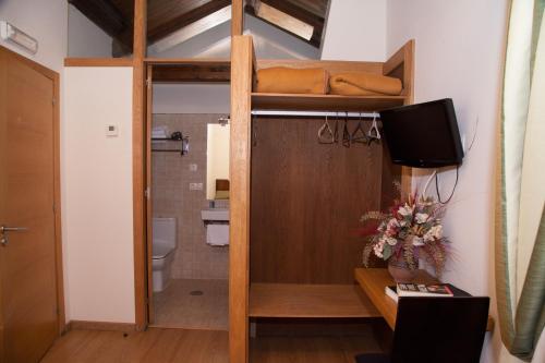 a room with a bunk bed with a television and a bathroom at Hotel Boa Vila in Pontevedra