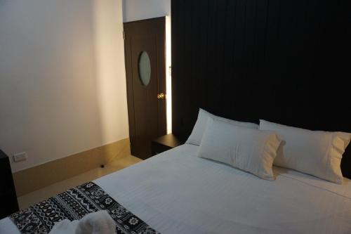 a bedroom with a large white bed with a black headboard at Holiday Hire Fiji in Lautoka
