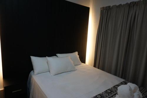 a bedroom with a white bed with white pillows at Holiday Hire Fiji in Lautoka