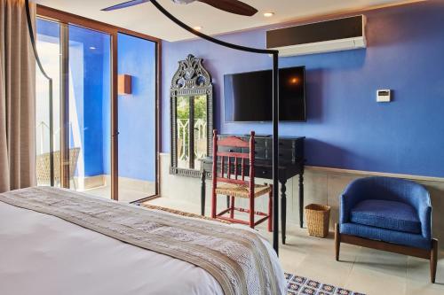 a bedroom with a blue wall with a bed and a chair at Hotel Luxury Patio Azul in Puerto Vallarta