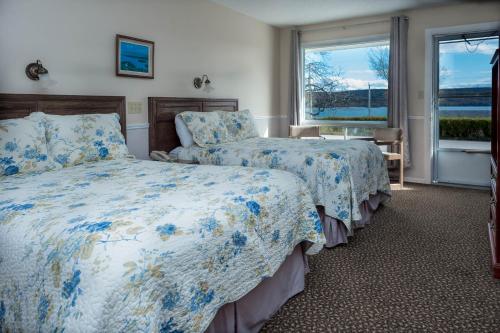 um quarto de hotel com duas camas e uma janela em Cabot Trail Motel em Baddeck