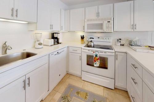 a white kitchen with white cabinets and a sink at Perfect location & Unbelievable Views at Lahaina Roads in Lahaina