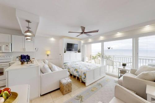 a white bedroom with a bed and a balcony at Perfect location & Unbelievable Views at Lahaina Roads in Lahaina