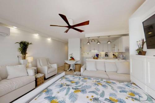 a living room with a white couch and a ceiling fan at Perfect location & Unbelievable Views at Lahaina Roads in Lahaina