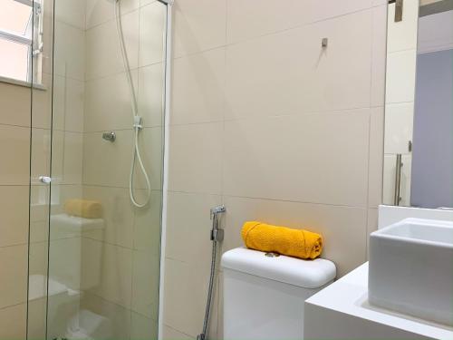 La salle de bains est pourvue d'une douche et d'une serviette jaune sur les toilettes. dans l'établissement Conforto em Copacabana- 100m da praia - BR1307 Z4, à Rio de Janeiro
