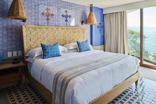 a bedroom with a large bed with blue walls at Hotel Luxury Patio Azul in Puerto Vallarta
